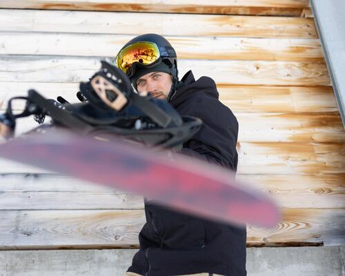 Snowboardzista trzymający deskę w goglach