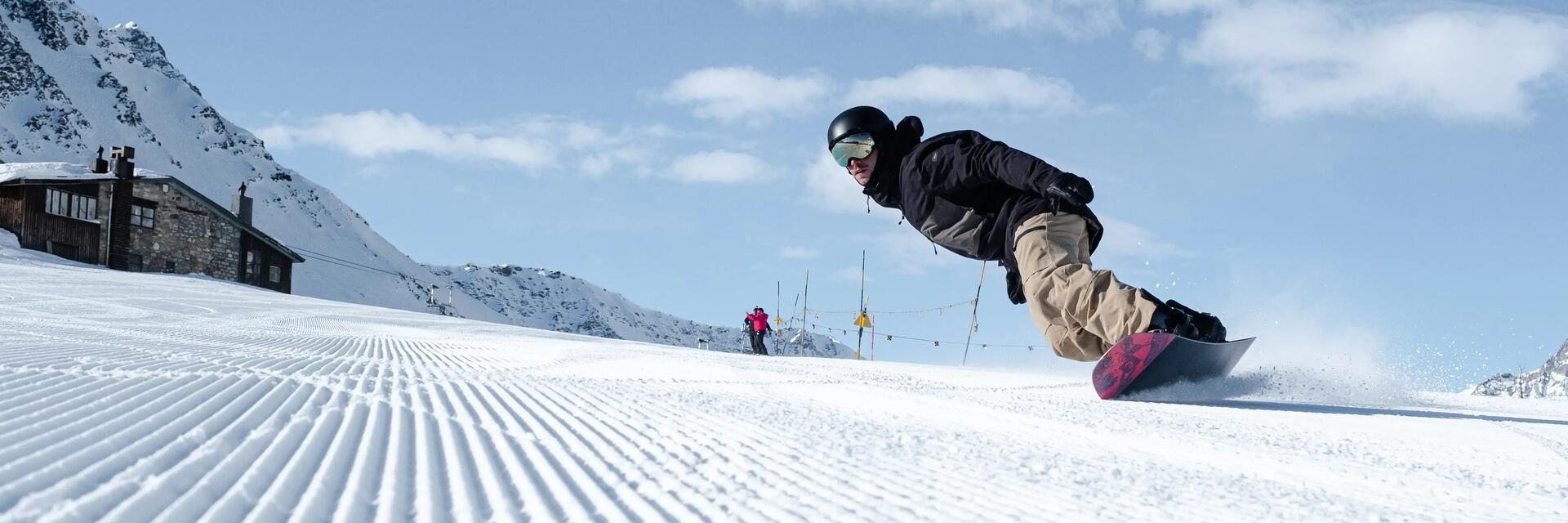 Mężczyzna w kasku i w goglach jeżdżący na snowboardzie