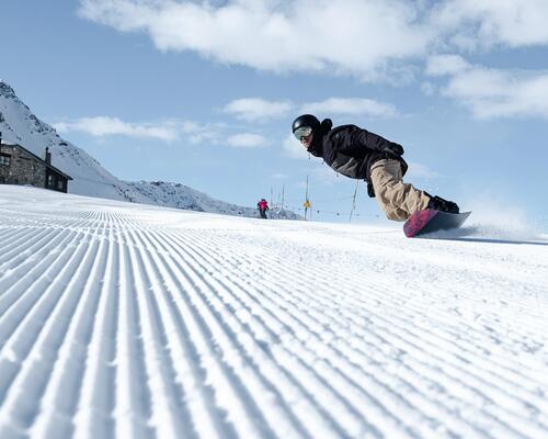 Mężczyzna w kasku i w goglach jeżdżący na snowboardzie