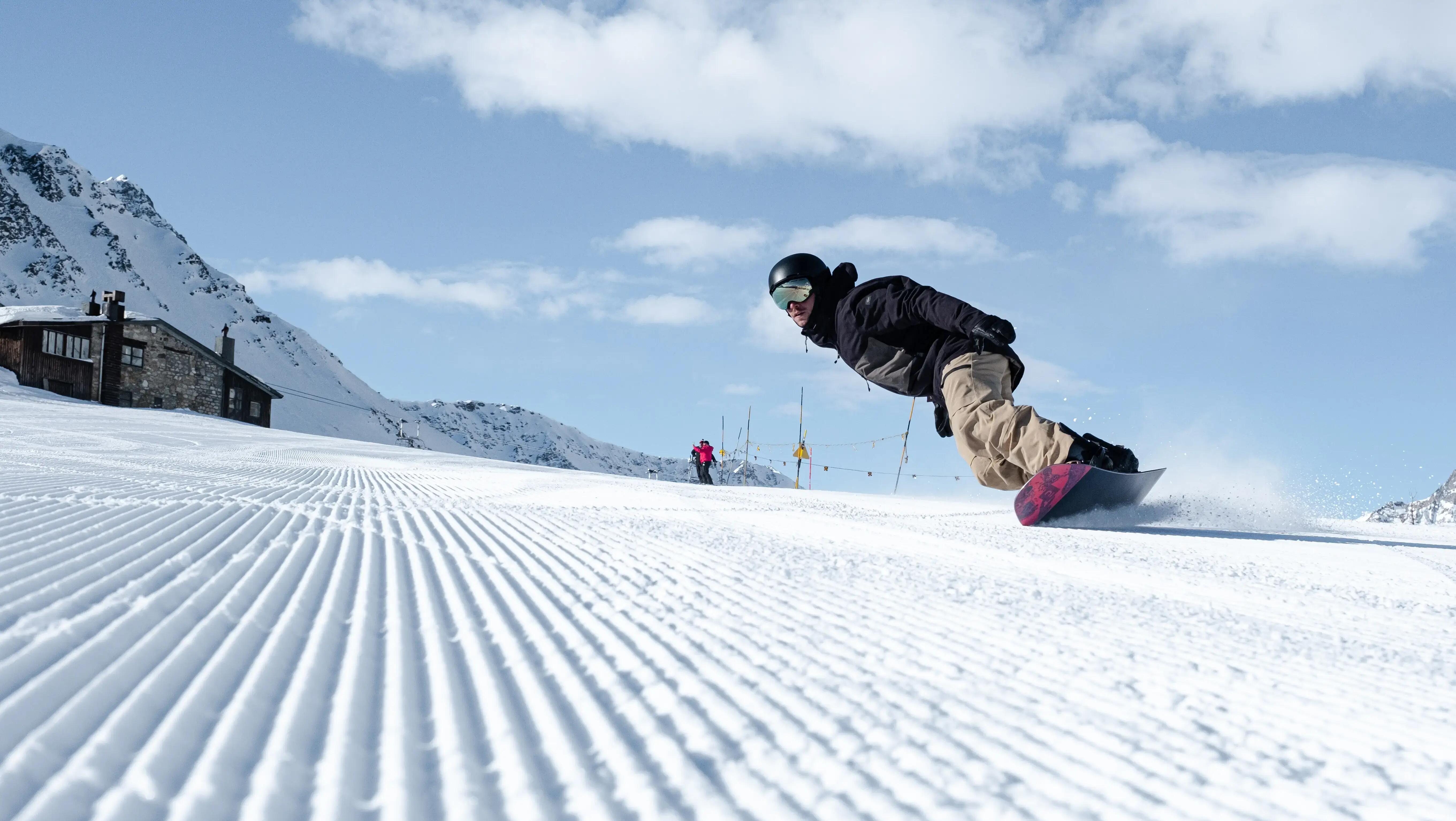 Snowboardista na zjazdovke pri horskej chate
