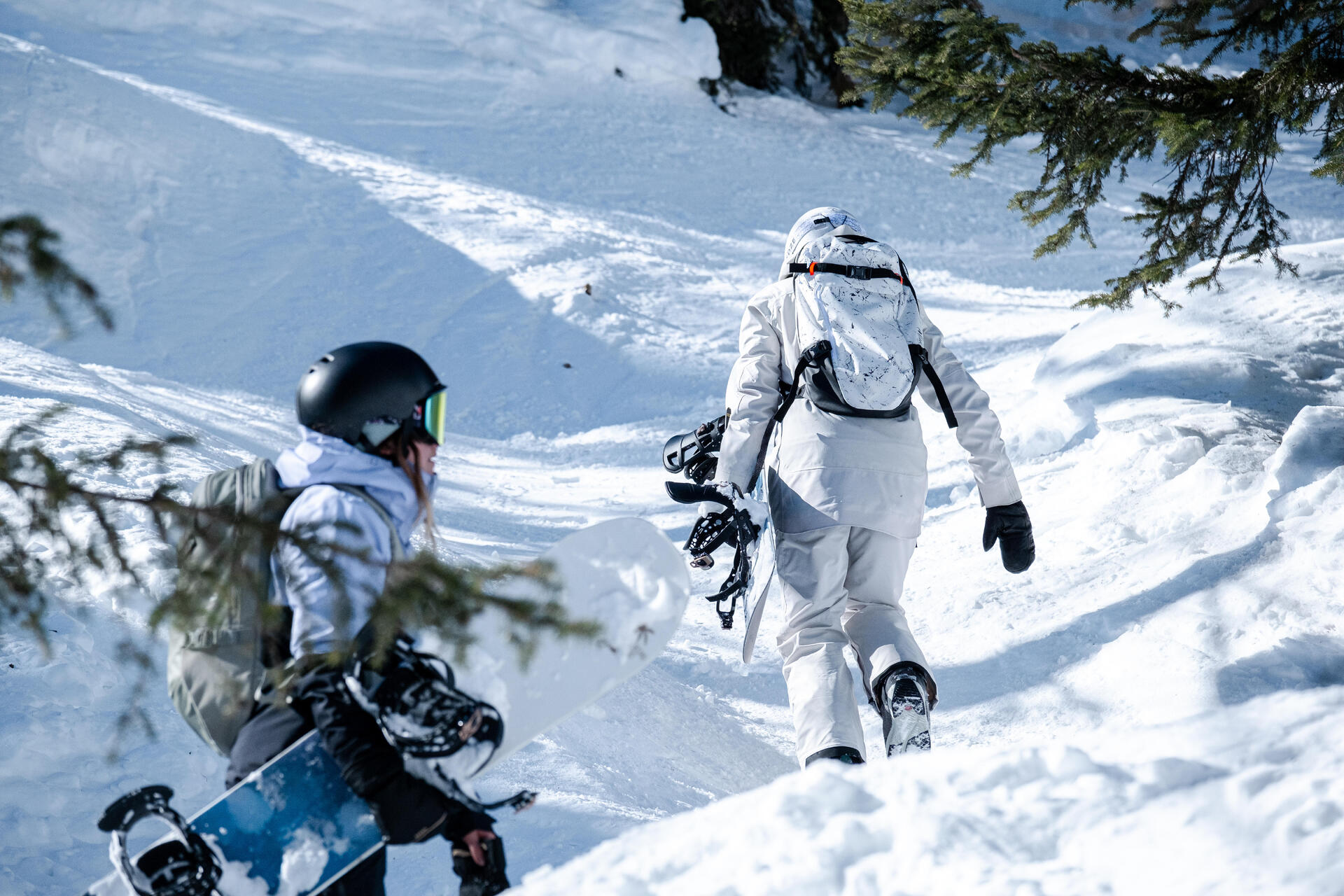 Para w odzieży snowboardowej z deskami pod pachą idąca na stok