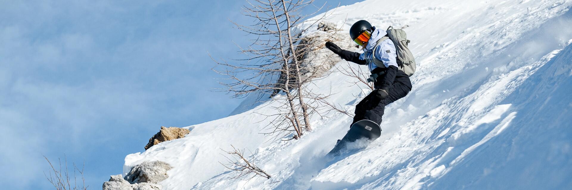 chłopiec w kasku i goglach snowboardowych zjeżdżający na desce snowboardowej ze stoku