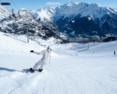 Osoba w odzieży zimowej skręcająca na snowboardzie