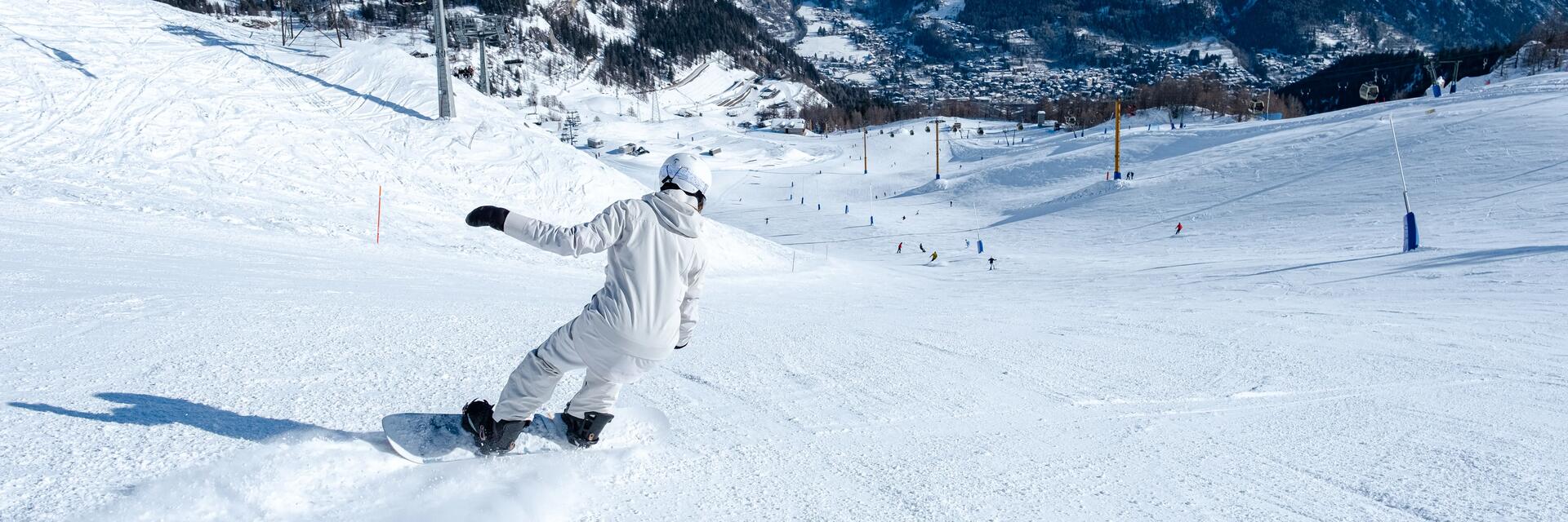 Osoba w odzieży zimowej skręcająca na snowboardzie