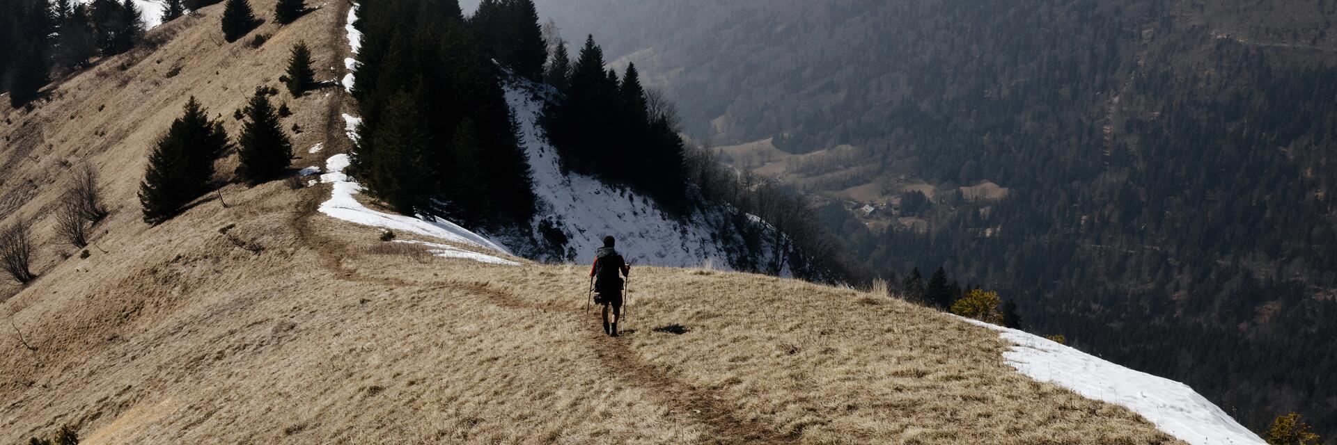 Osoba idąca do schroniska w górach z zapakowanym plecakiem turystycznym na plecach 