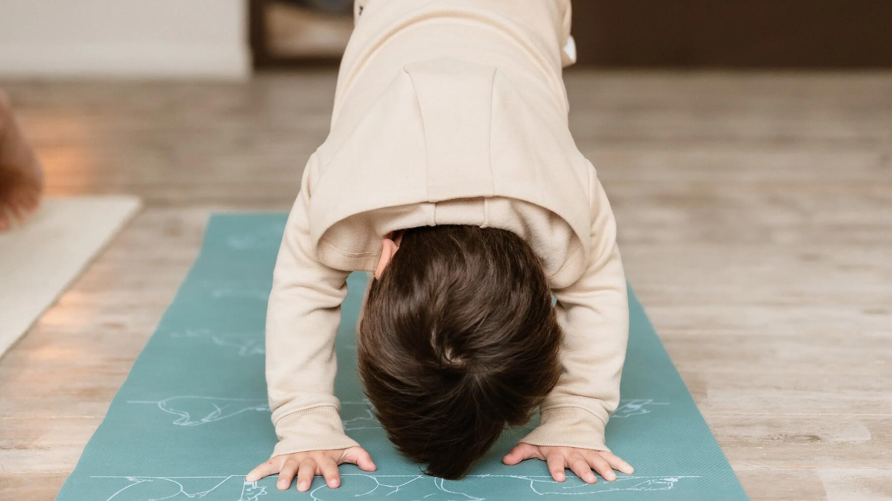 Kleines Kind auf blauer Kinder Yogamatte in Asana.