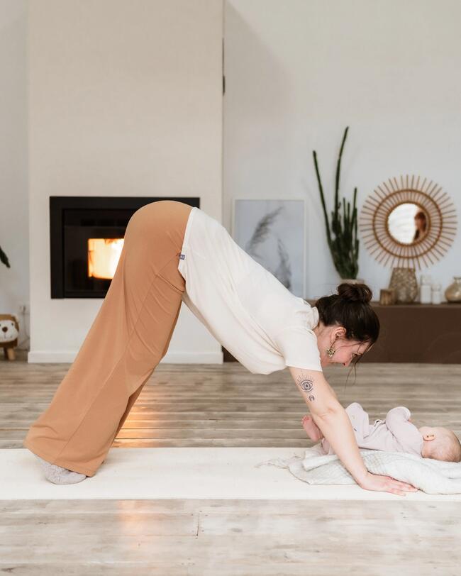 Eine Frau macht Yoga mit ihrem Baby. 