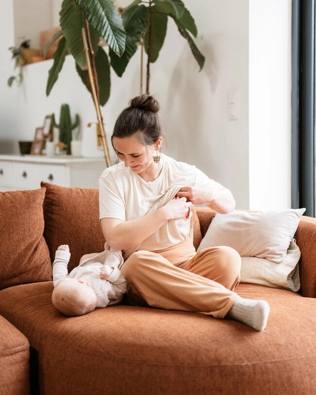 Eine Frau sitzt mit ihrem Baby auf dem Sofa.