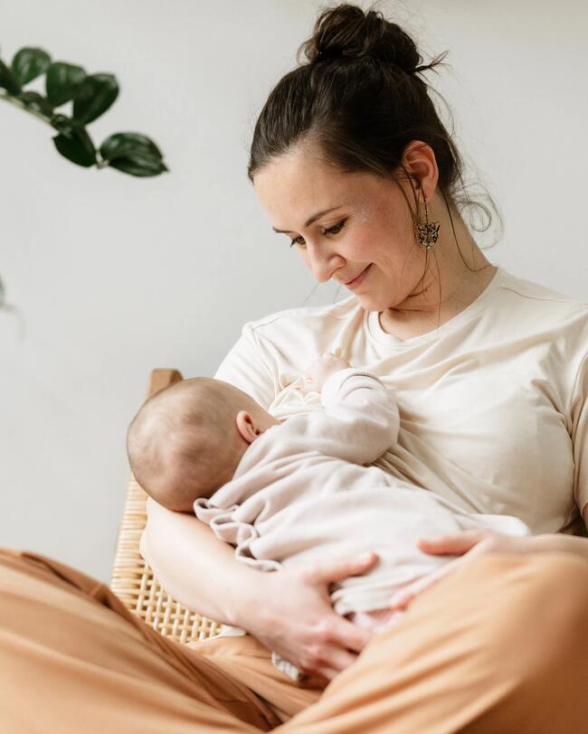 Eine Frau sitzt mit ihrem Baby auf dem Sofa.
