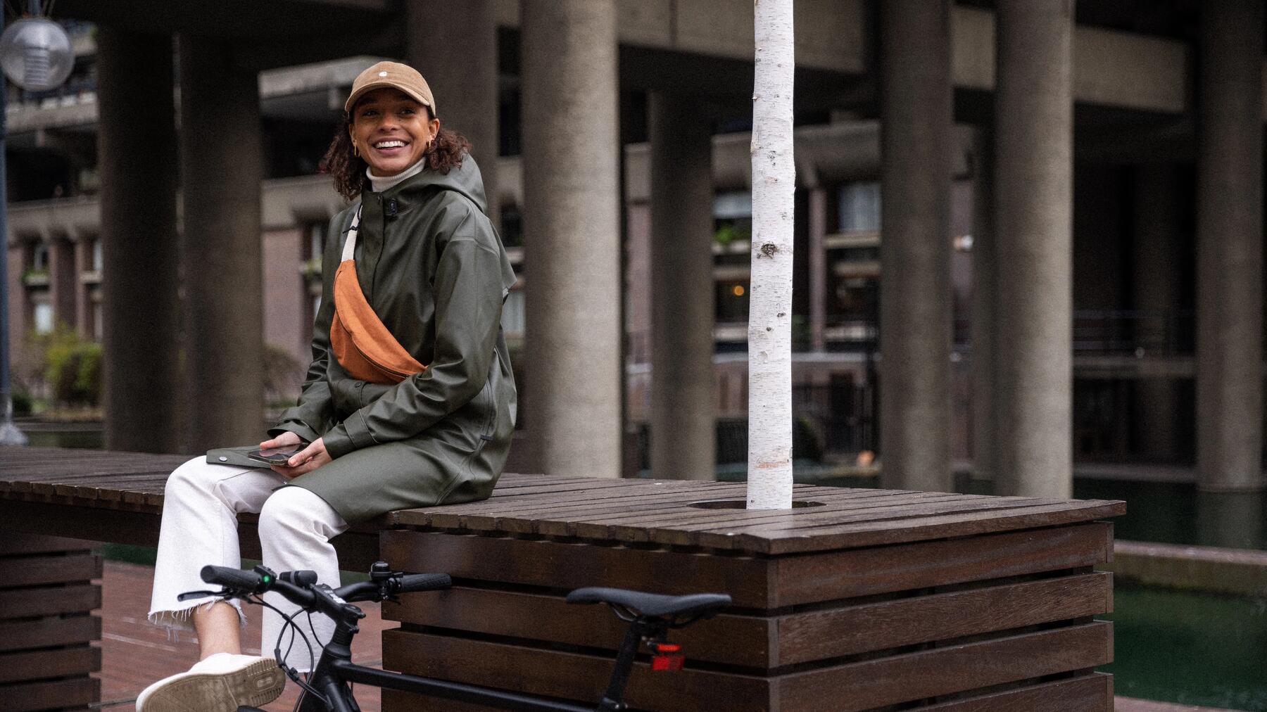 Kobieta siedząca na ławce w mieście obok roweru fitnessowego