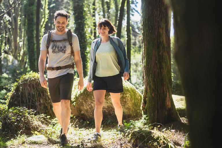 Man and woman wearing hiking shorts while walking through a forest