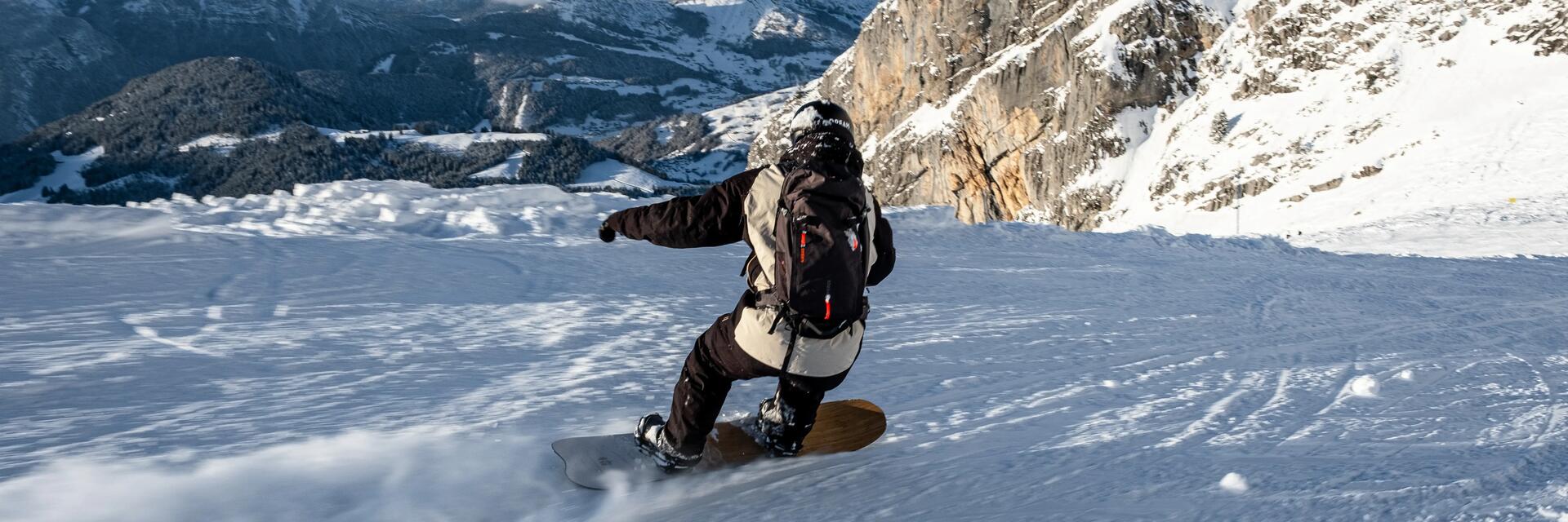 Mężczyzna w odzieży snowboardoej jadący ze stoku na desce snowboardowej dobranej do wzrostu i wagi 