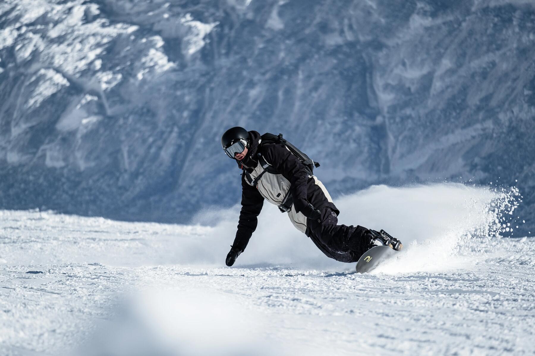 Mężczyzna w odzieży zimowej w kasku i w goglach jeżdżący na snowboardzie