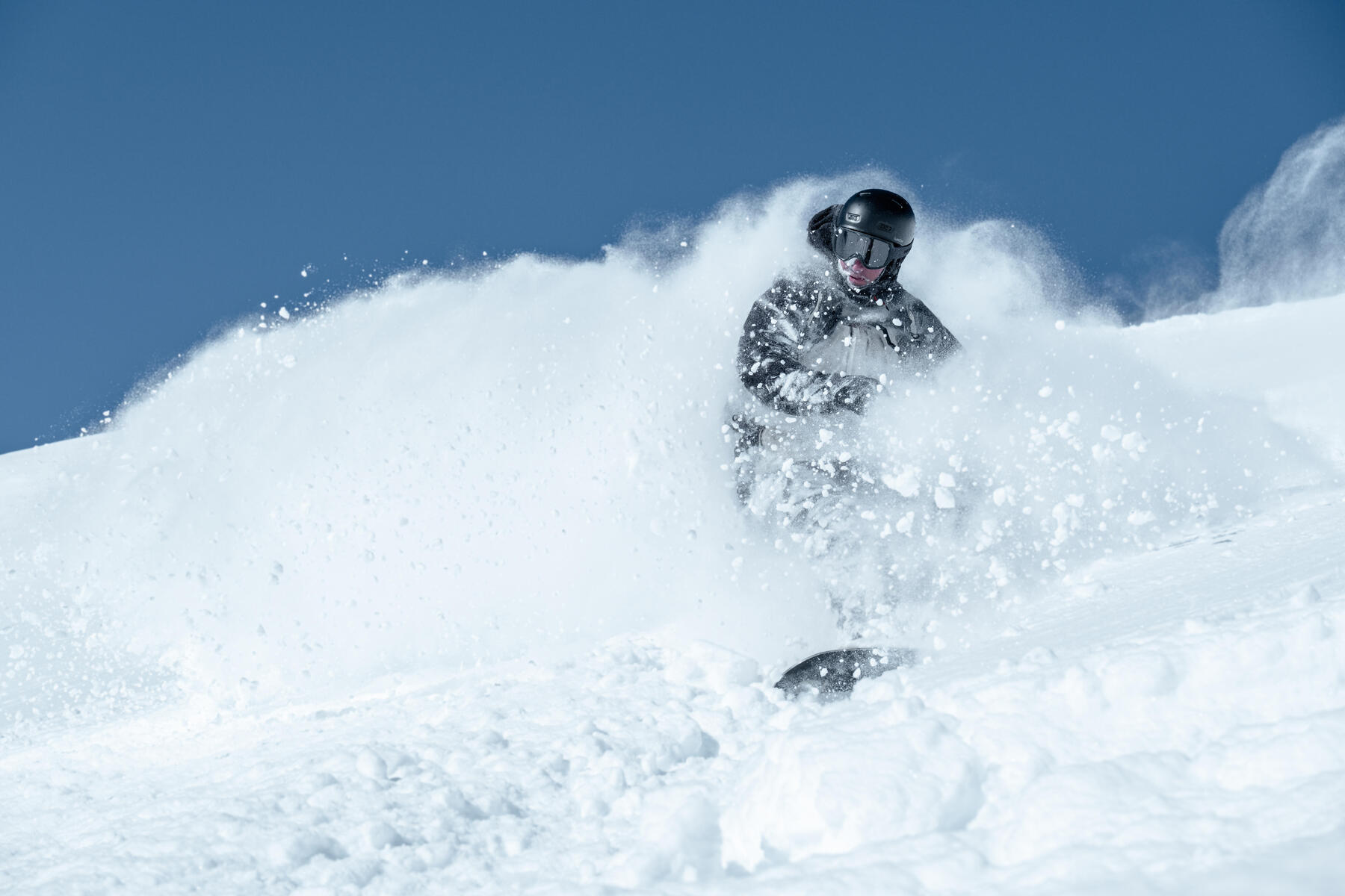 Mężczyzna w odzieży zimowej w kasku jeżdżący na snowboardzie