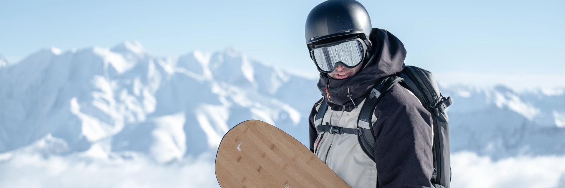 Mężczyzna na stoku stojący z deską snowboardową