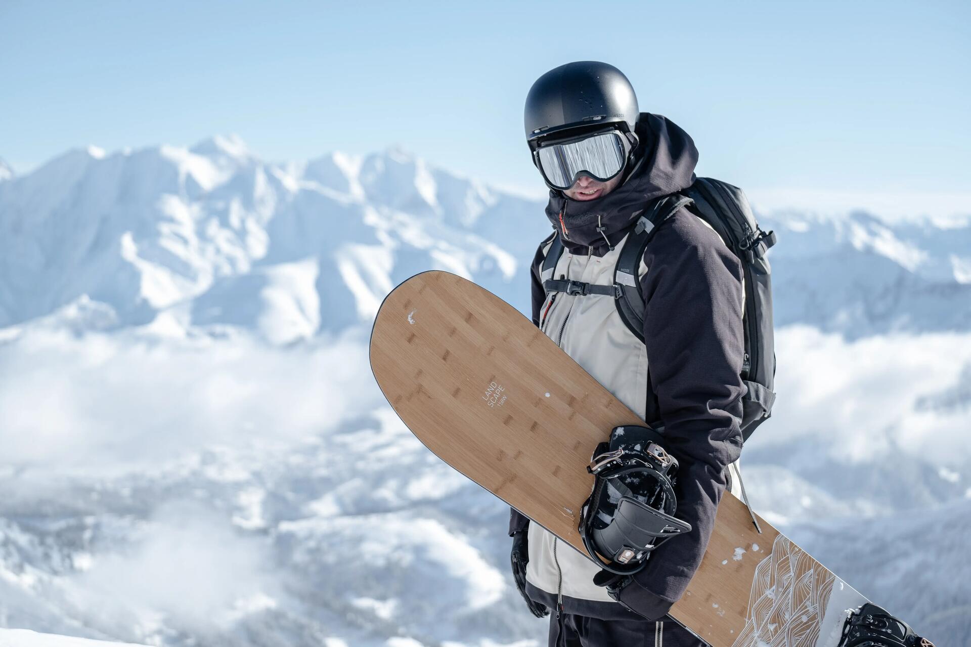 mężczyznaa w kasku i goglach zjeżdżająca na desce snowboardowej