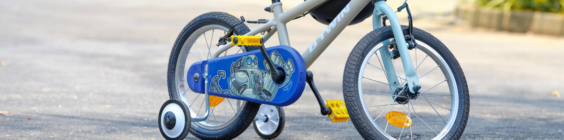rower dziecięcy z bocznymi kółkami z zawieszonym kaskiem rowerowym