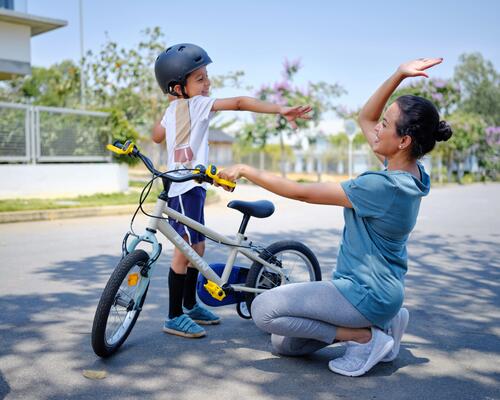 kobieta  i chłopiec w kasku stojący przy rowerze dziecięcym