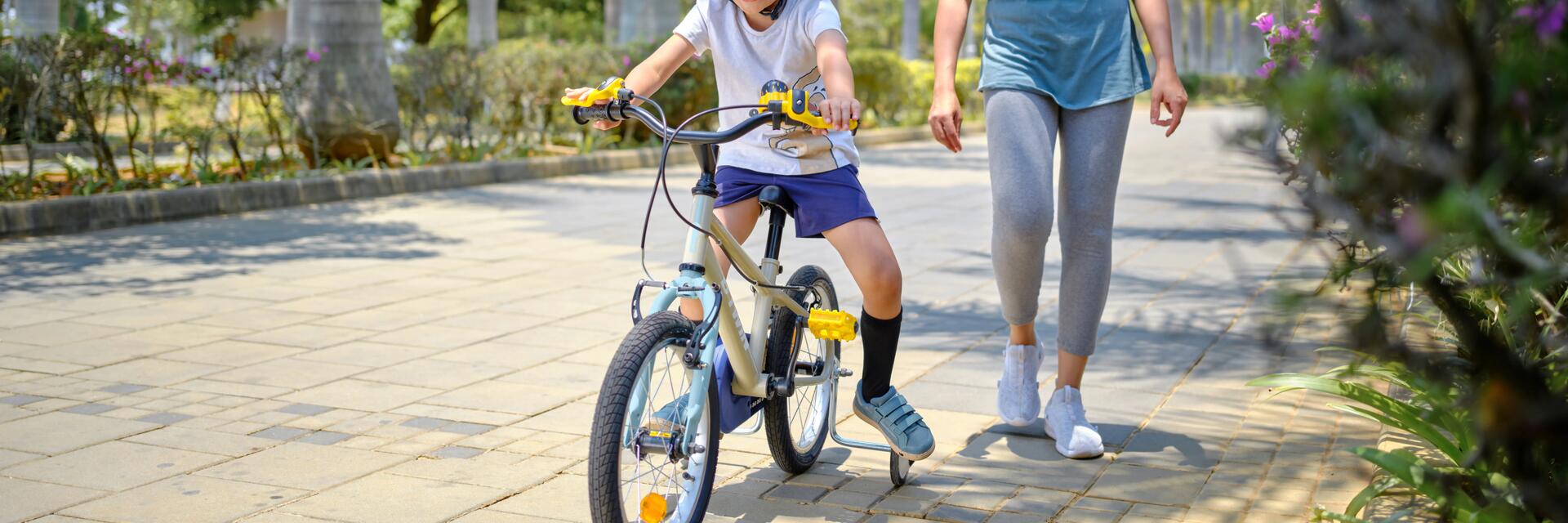 6 latek jadący na rowerze za nim idąca mama