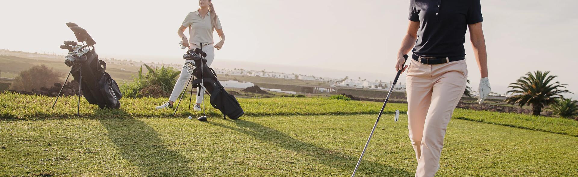 Kobieta ubrana w strój i buty do golfa trzymająca kij golfowy