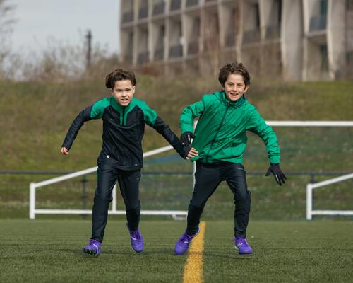 chłopcy w ciepłych ubraniach piłkarskich trenujący piłkę nożną zimą na boisku
