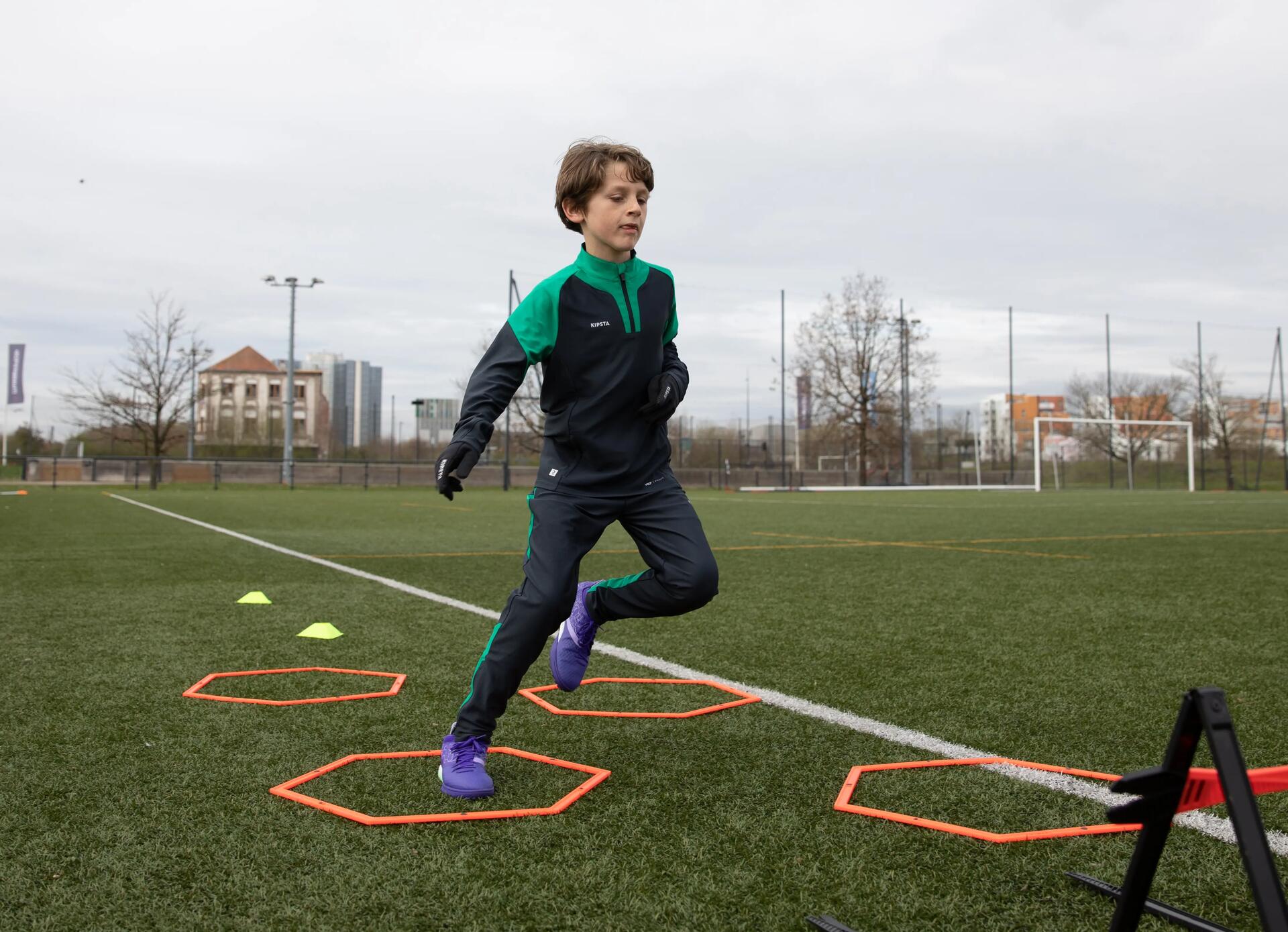 chłopiec w rękawiczkach i zimowym stroju piłkarski podczas treningu piłki nożnej na boisku zimą 