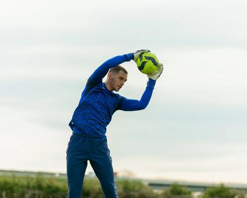 Bramkarz rozciągający się z piłką w rękach