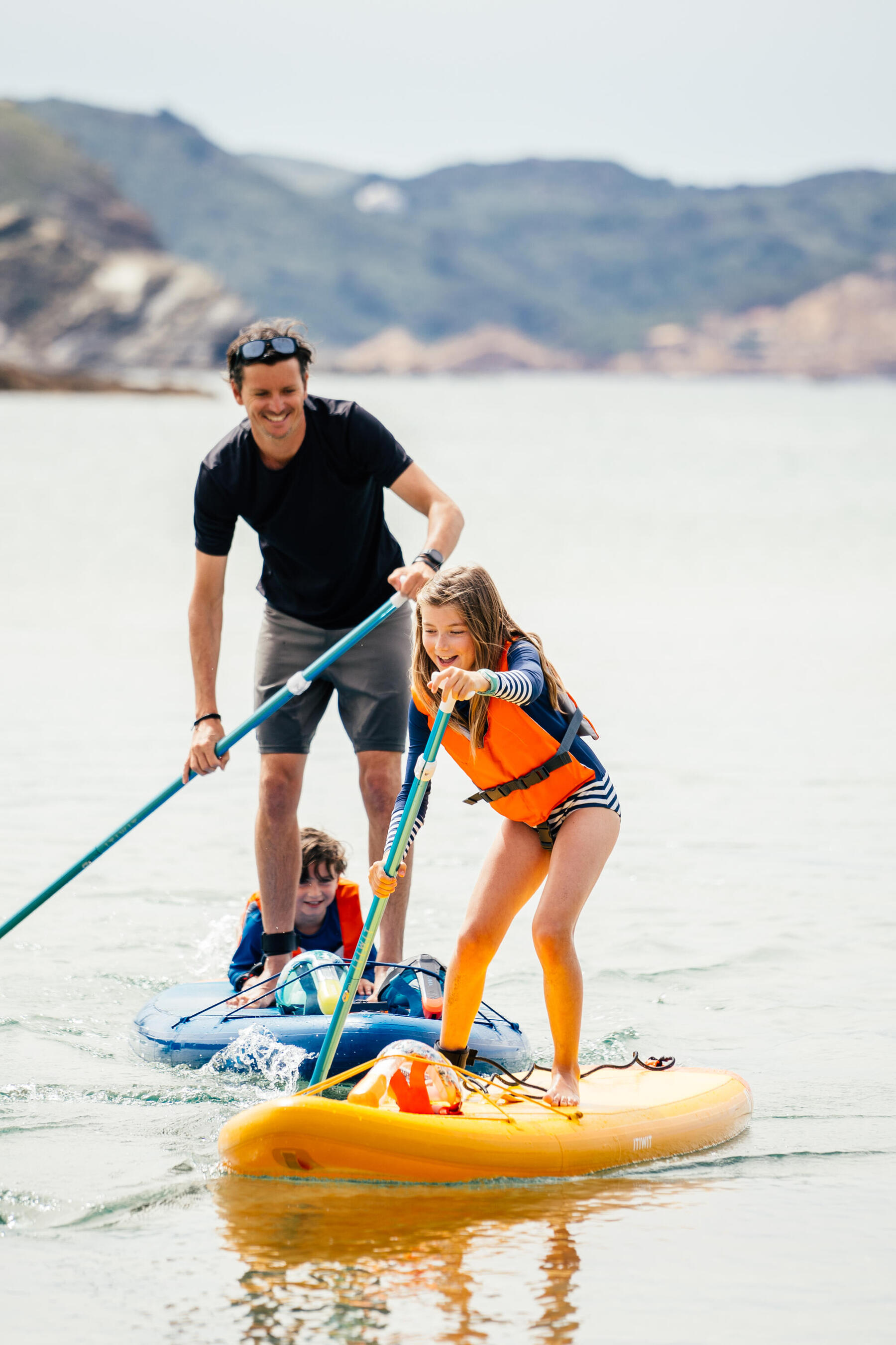 Mann steht mit seinen Kindern auf einem SUP und erkennt dabei die Vorteile