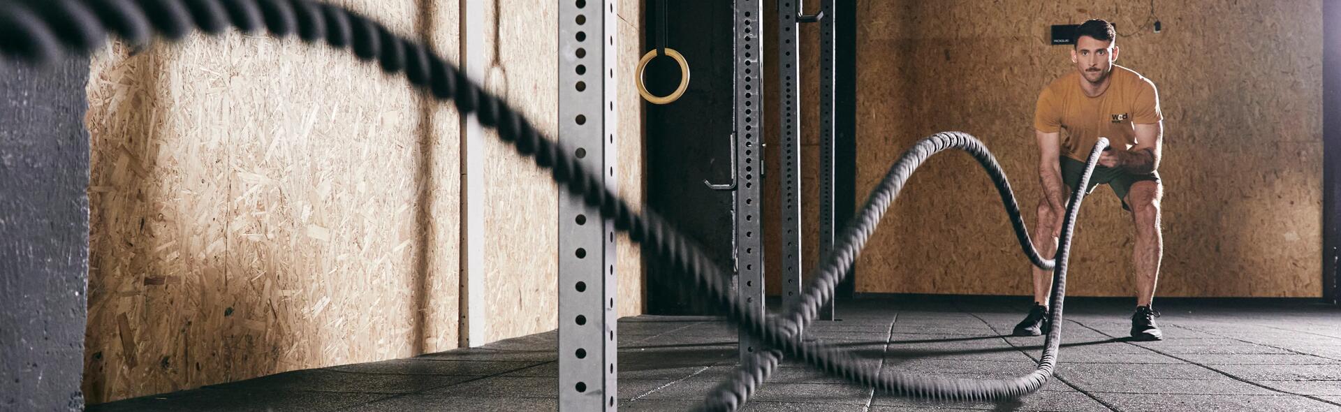 Mężczyzna robiący trening z linami nazywany battle rope