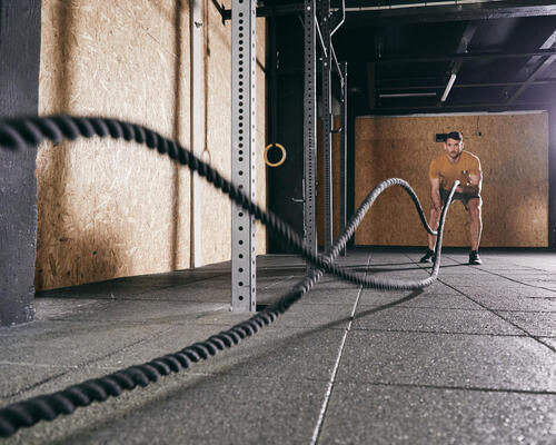 Mężczyzna robiący trening z linami nazywany battle rope