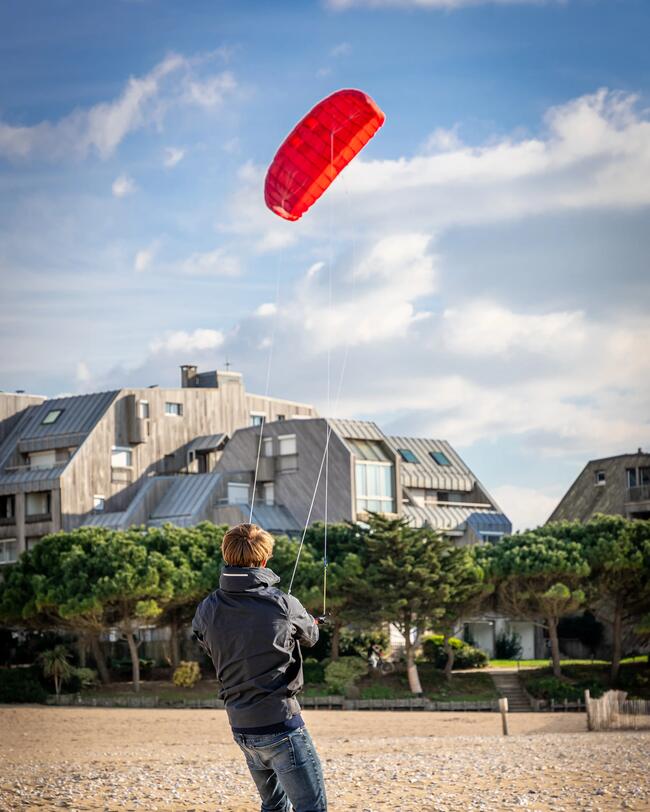 Cometa de tracción roja volando sobre la playa.