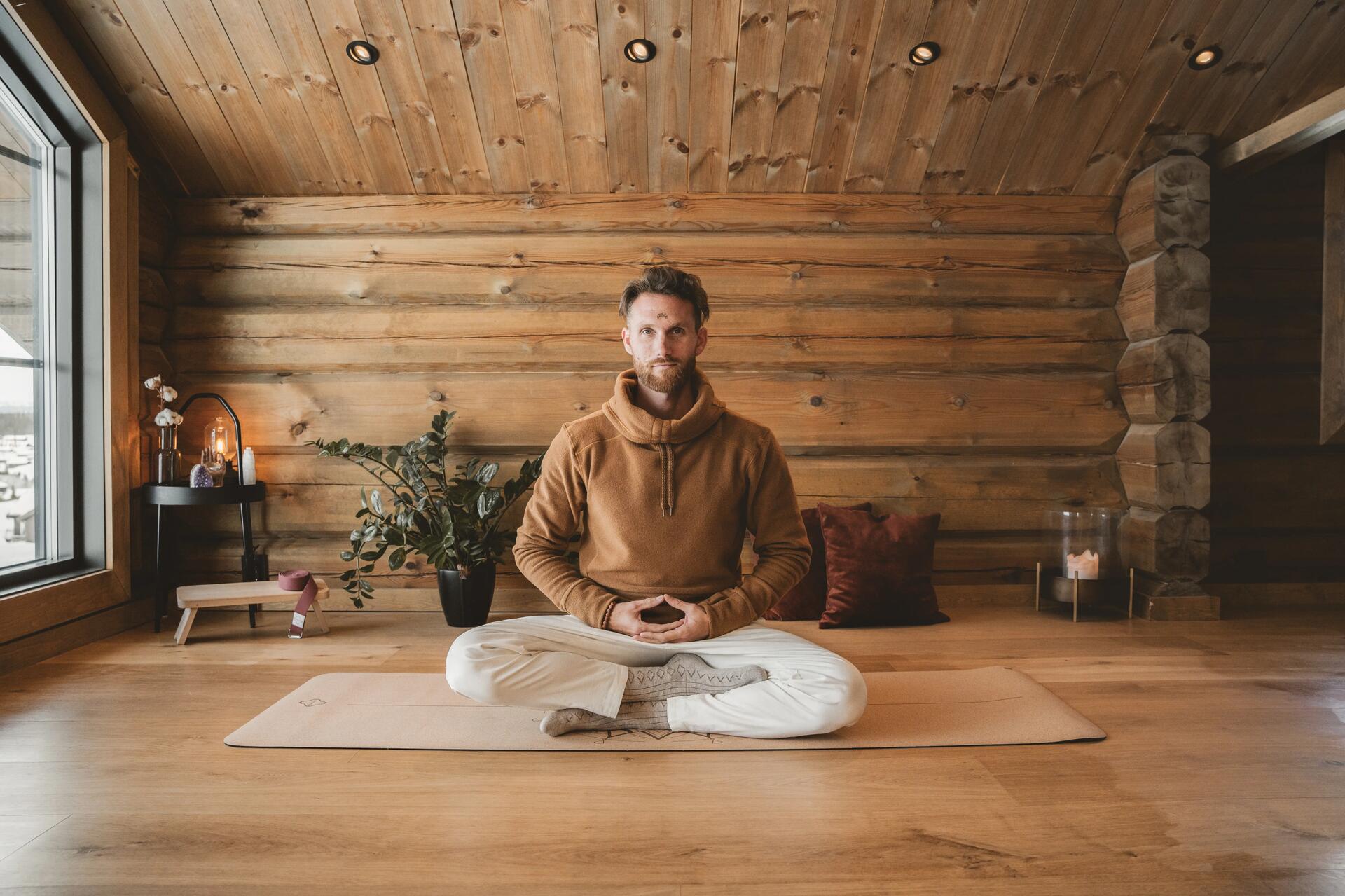Mężczyzna praktykujący oddech ognia siedząc w pozycji lotosu na macie do jogi