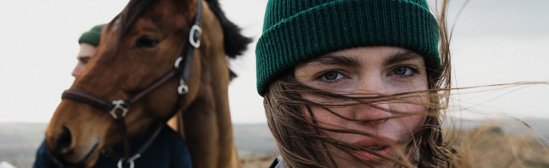 dziewczyna w czapce stojąca obok konia