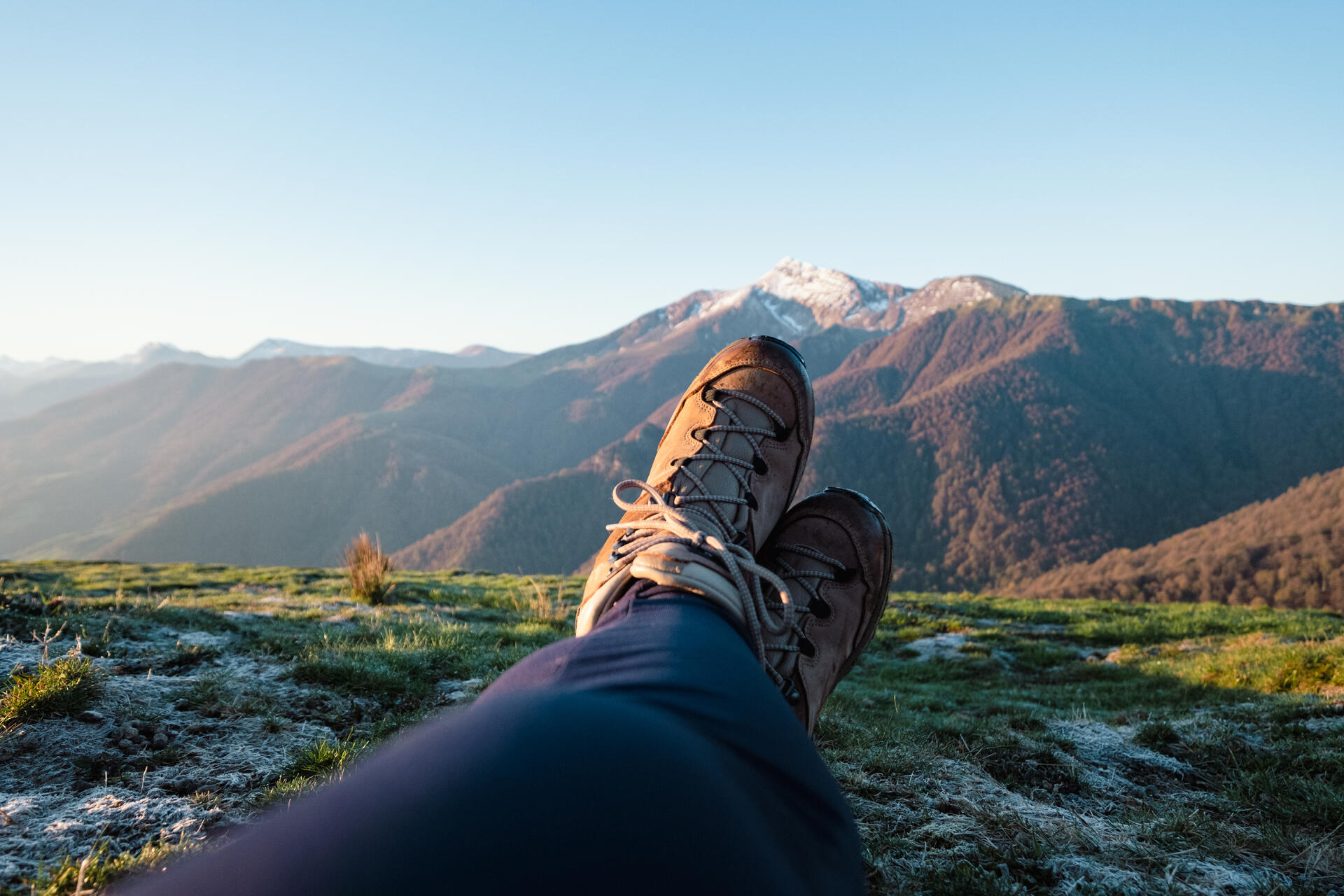 osoba leżąca na trawie w górach w butach trekkingowych