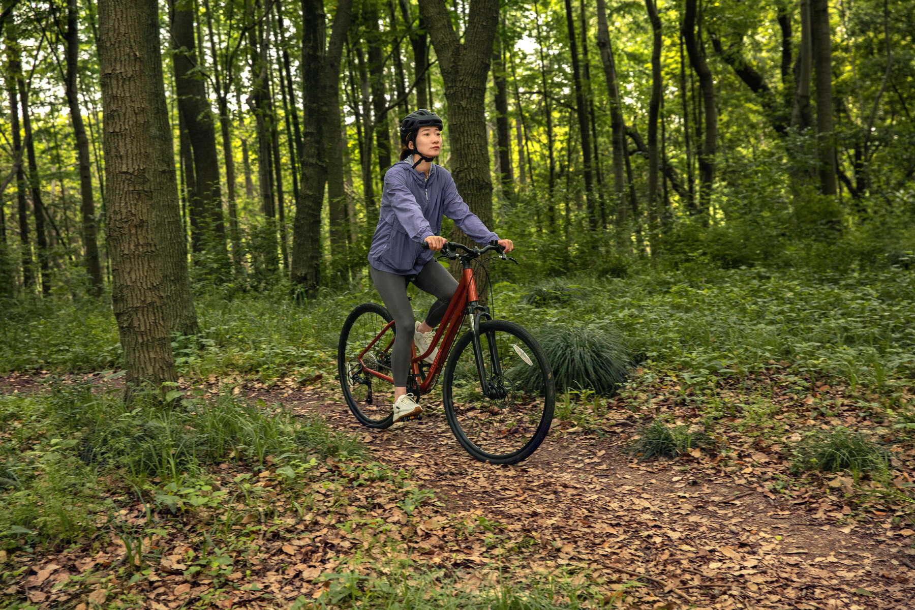 Kobieta jadąca na rowerze trekkingowym po lesie