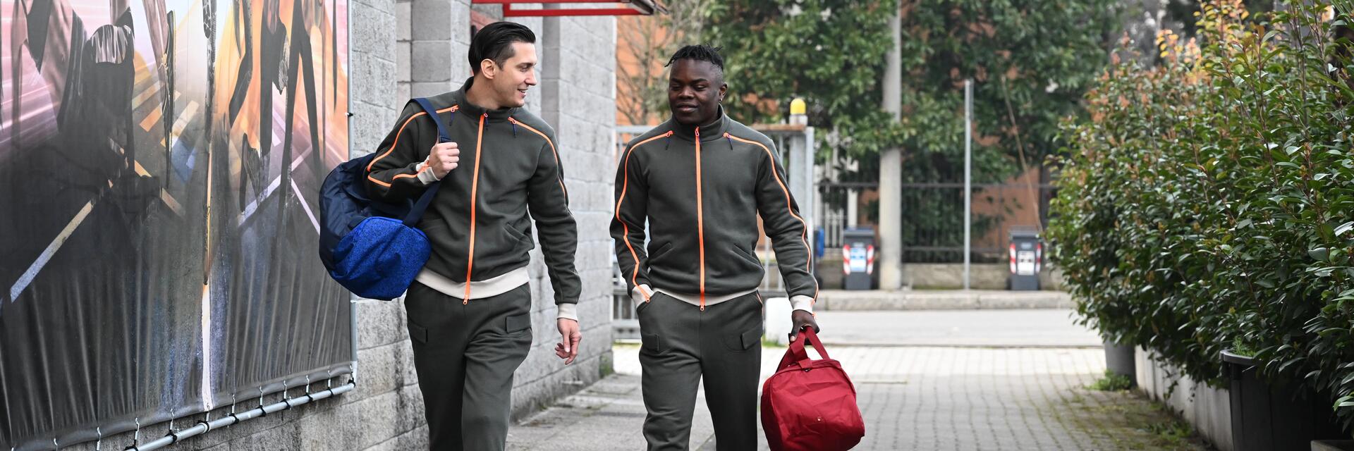 Mężczyźni w odzieży sportowej idący na trening trzymając torby na siłownię