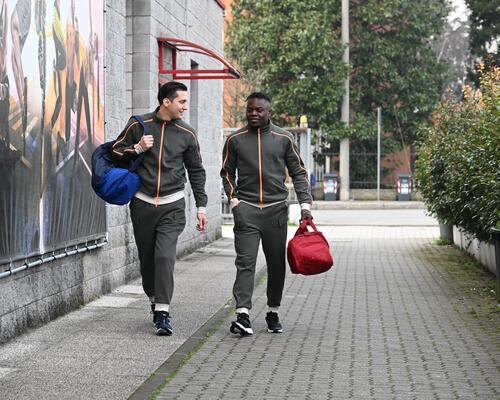 Mężczyźni w odzieży sportowej idący na trening trzymając torby na siłownię