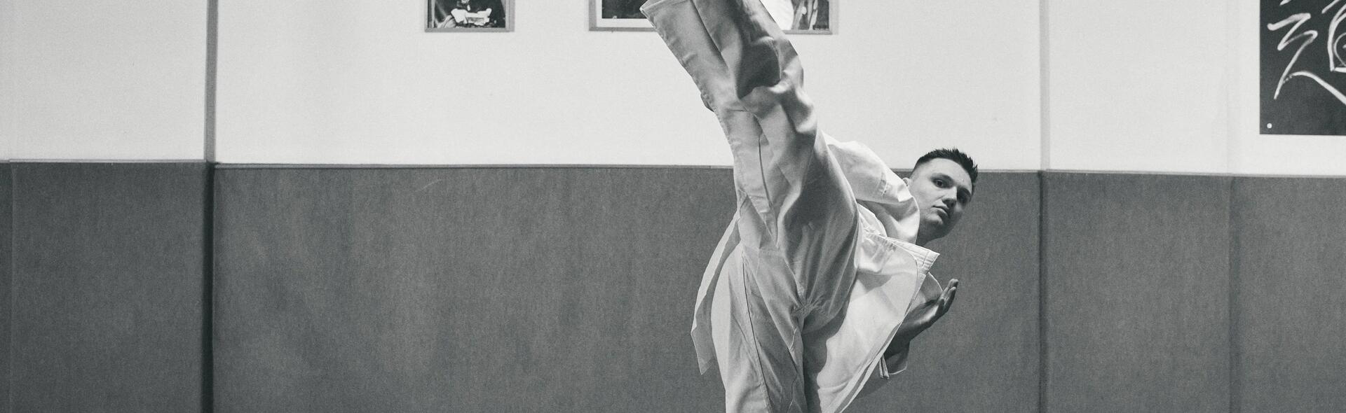 mężczyzna ubrany w dobok wykonujący kopnięcie taekwondo