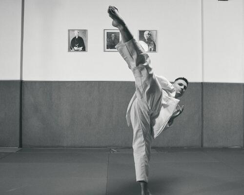 mężczyzna ubrany w dobok wykonujący kopnięcie taekwondo