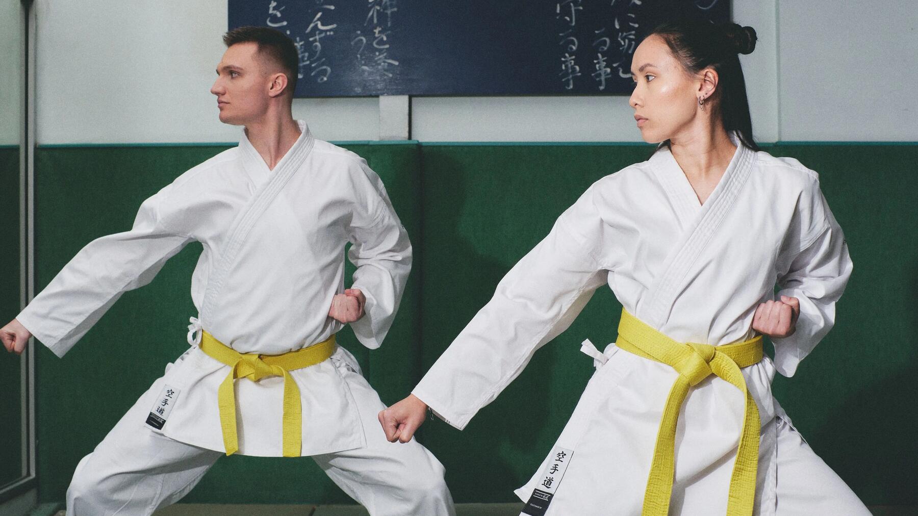 Synchrones Karate-Training: Ein Paar in traditionellen Gis in einer tiefen Kampfkunst-Position