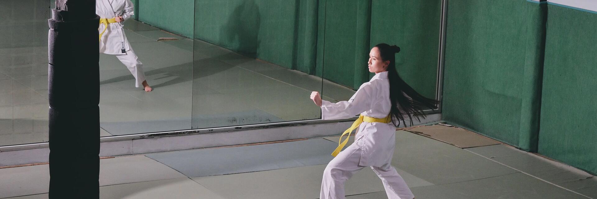 Kobieta szlifująca techniki Shaolin kung fu na sali przed lustrami