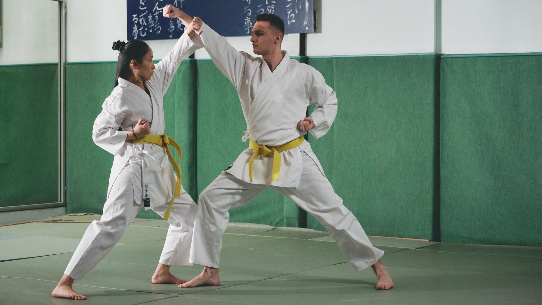 Mann und Frau in Karate-Gis mit oben gekreuzten Armen in einer Kampfposition