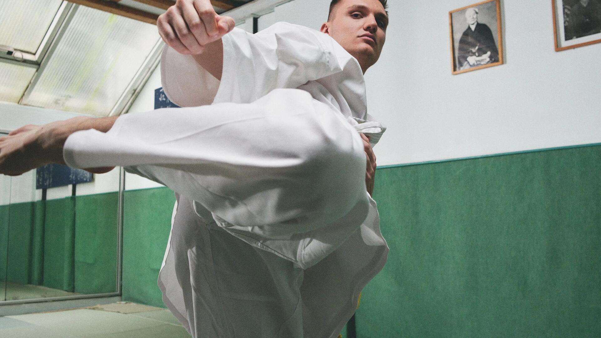 mężczyzna ubrany w kimono wykonujący kopnięcie taekwondo