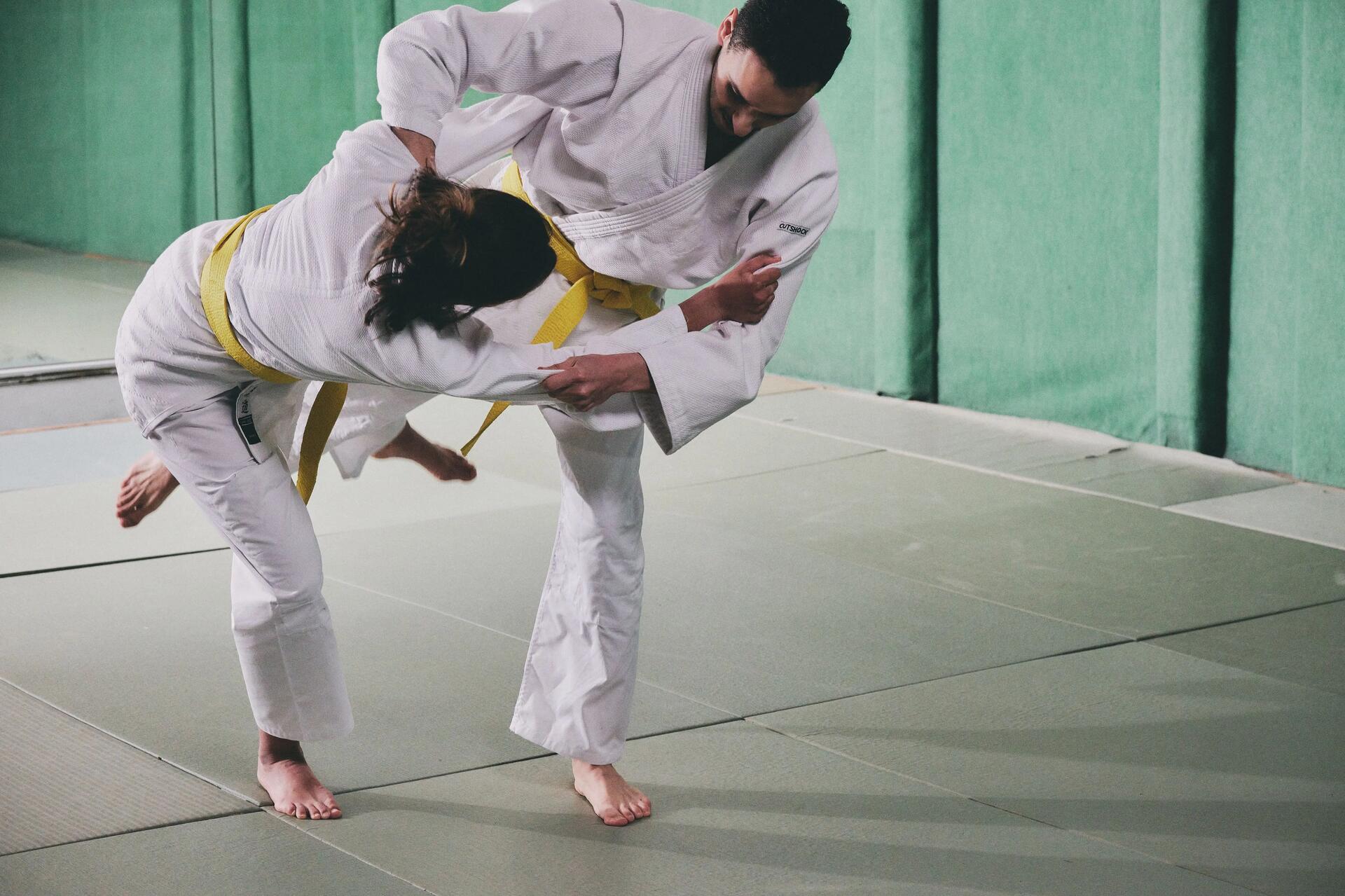 Kobieta i mężczyzna w karategach trenujący techniki aikido na sali treningowej