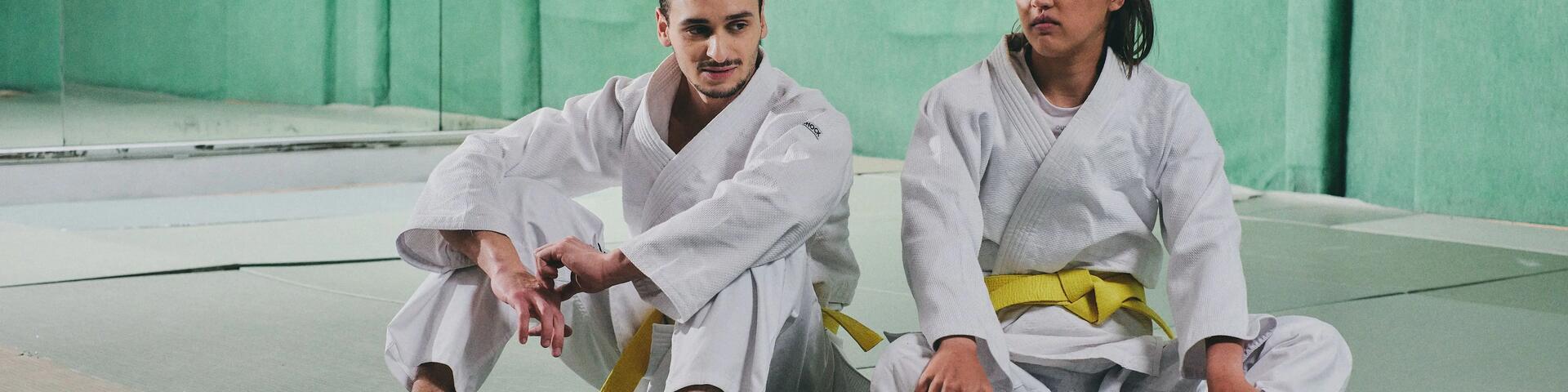 kobieta i mężczyzna siedzący na podłodze w strojach do trenowania sportów walki