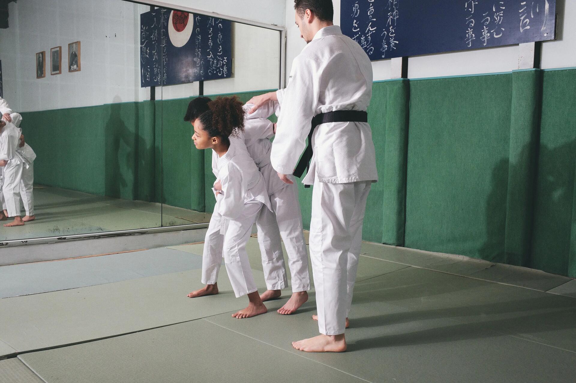 Dzieci trenujące sztuki walki judo przed lustrem z trenerem