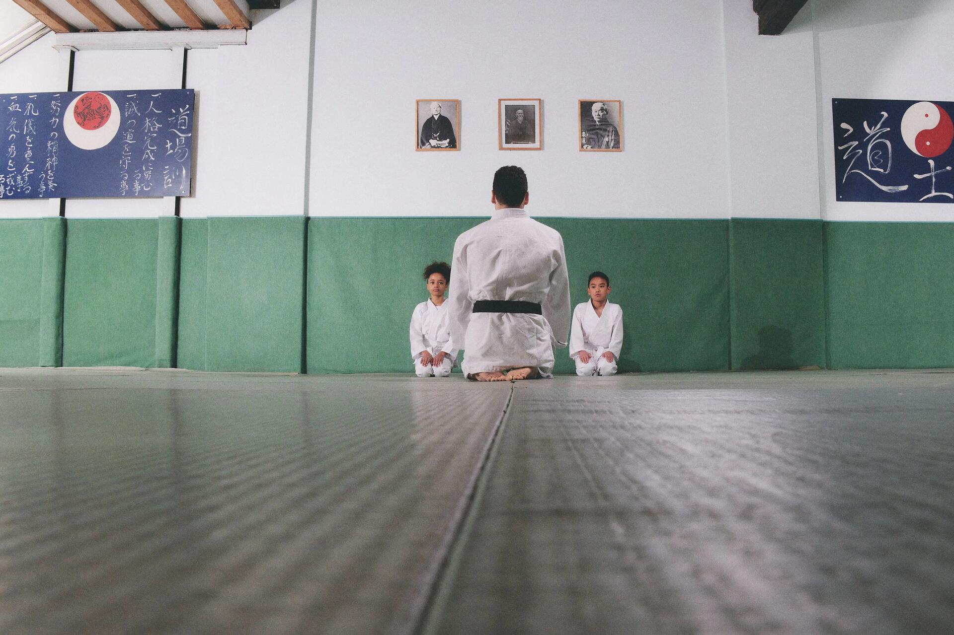 Zwei Kinder lernen gemeinsam mit ihrem Lehrer die moralischen Werte des Judo kennen