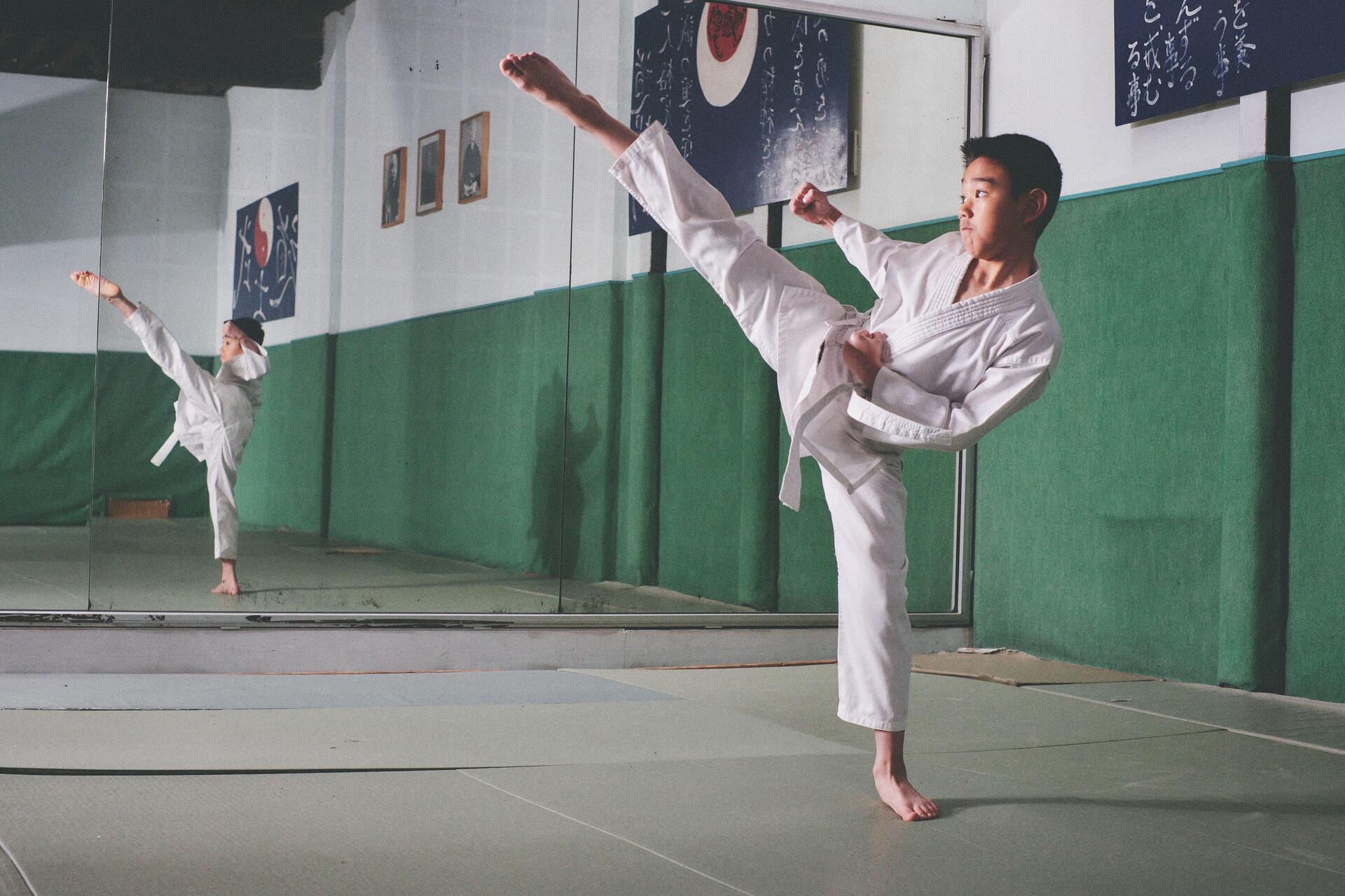 Nastolatek uprawiający sztuki walki karate przed lustrem na treningu