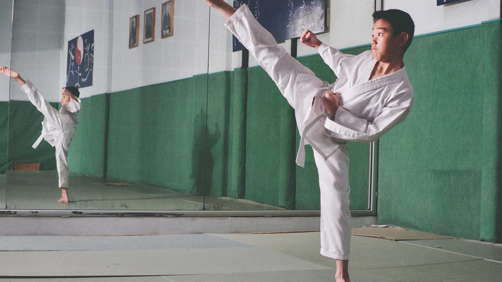 chłopiec ubrany w kimono trenujący karate