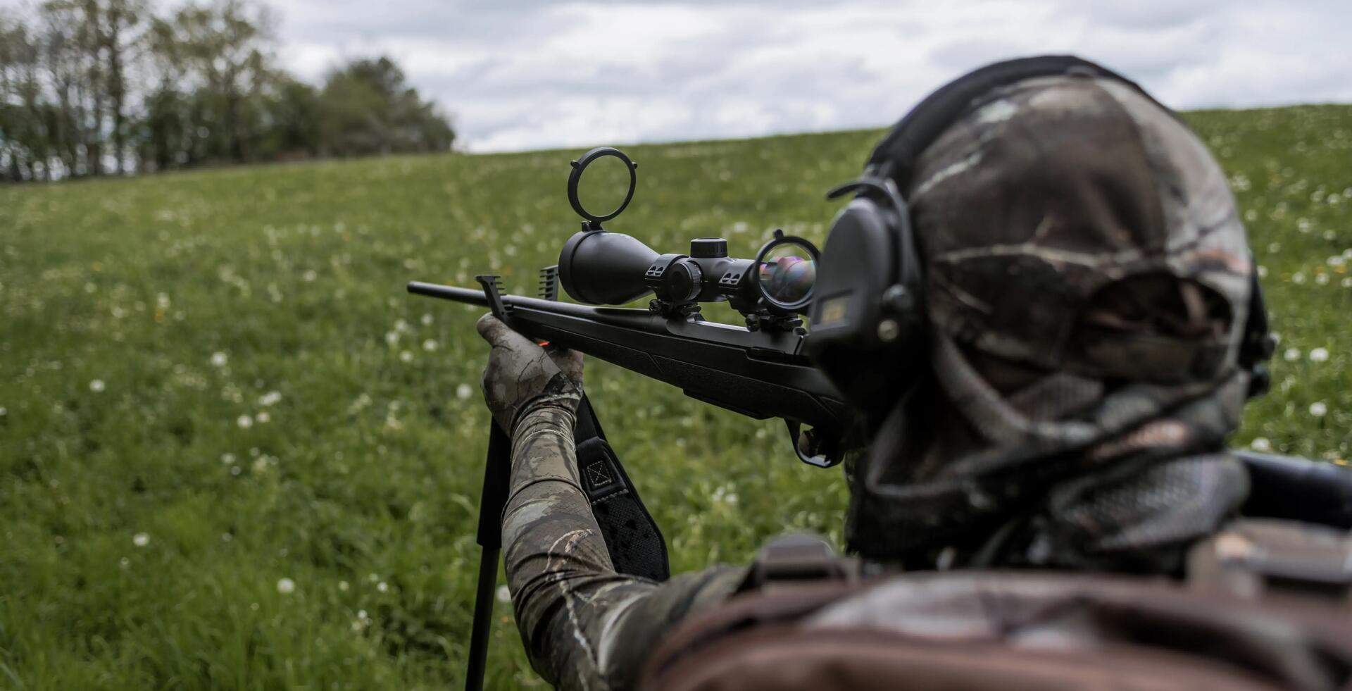 Un chasseur à l'approche avec une carabine sur une canne de pirsch